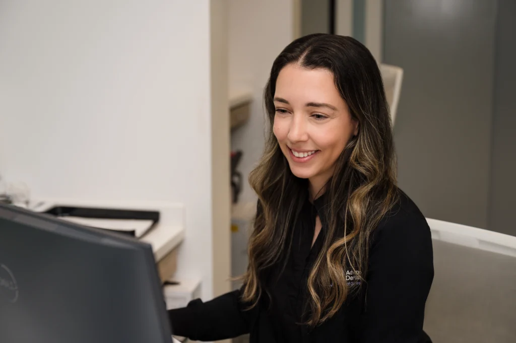 Kalla working at a computer workstation and smiling