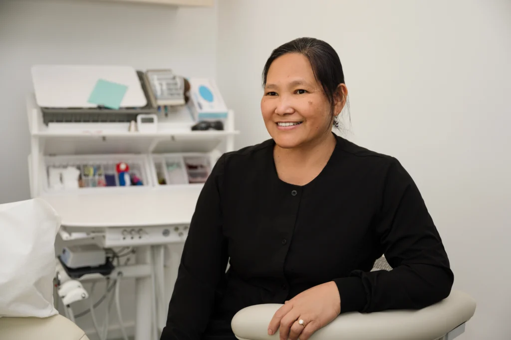 Raquel sitting next to an exam table smiling