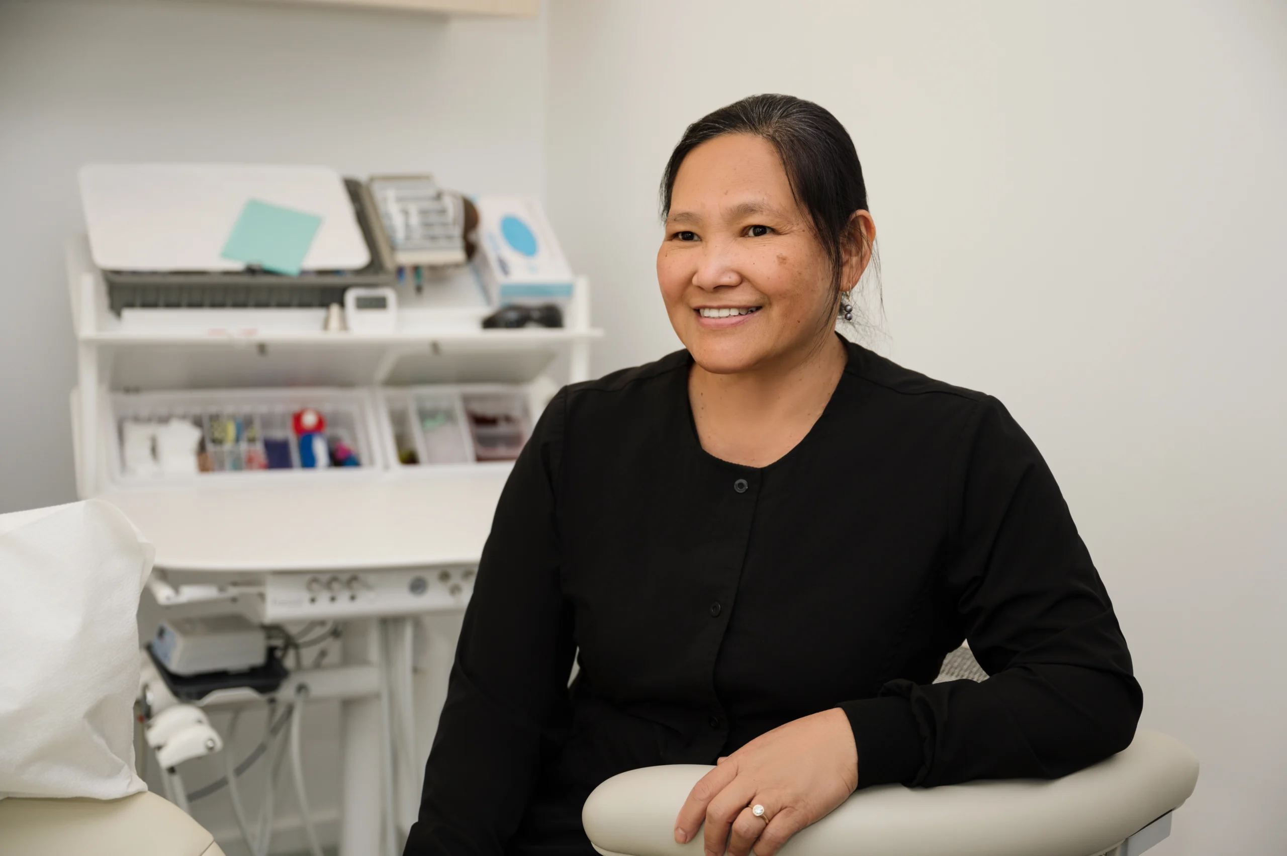Raquel sitting next to an exam table smiling
