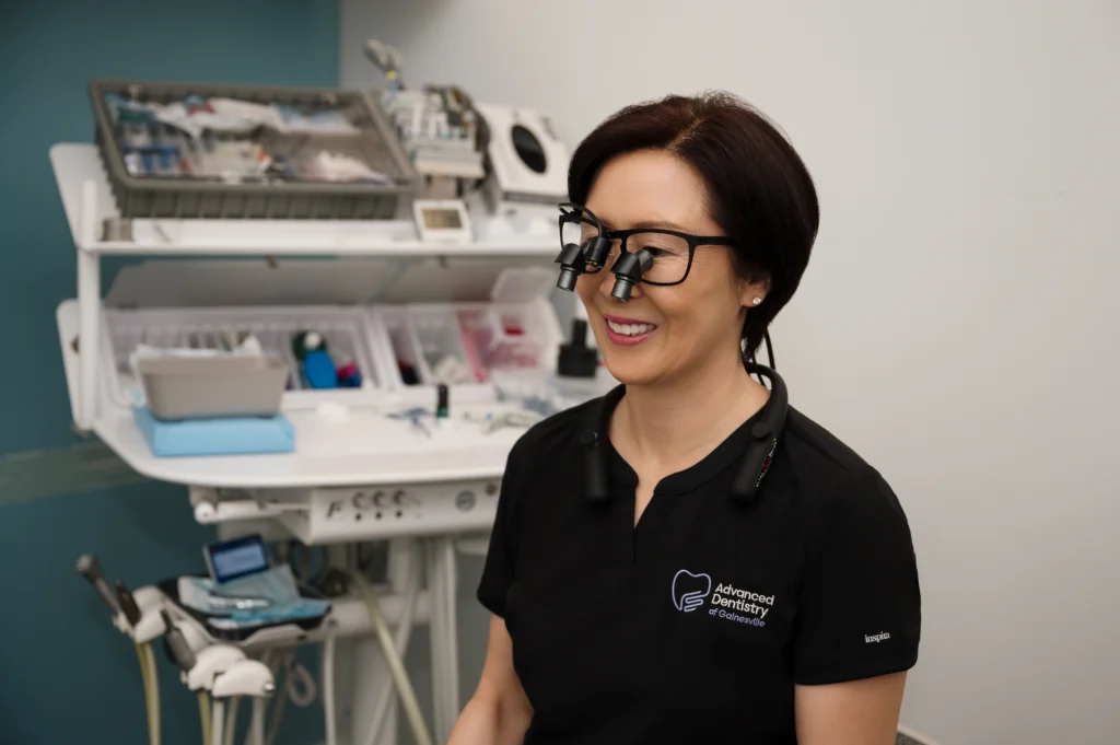 Ree wearing magnification glasses and smiling in an exam room