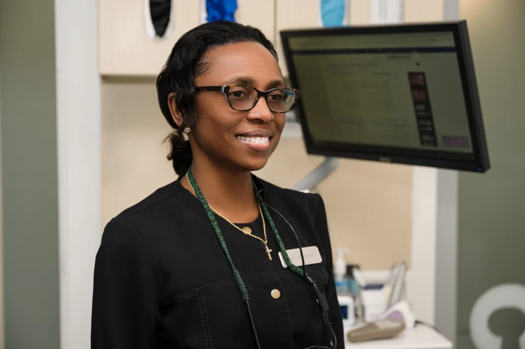 Regeina standing in front of an informational display smiling in an exam room