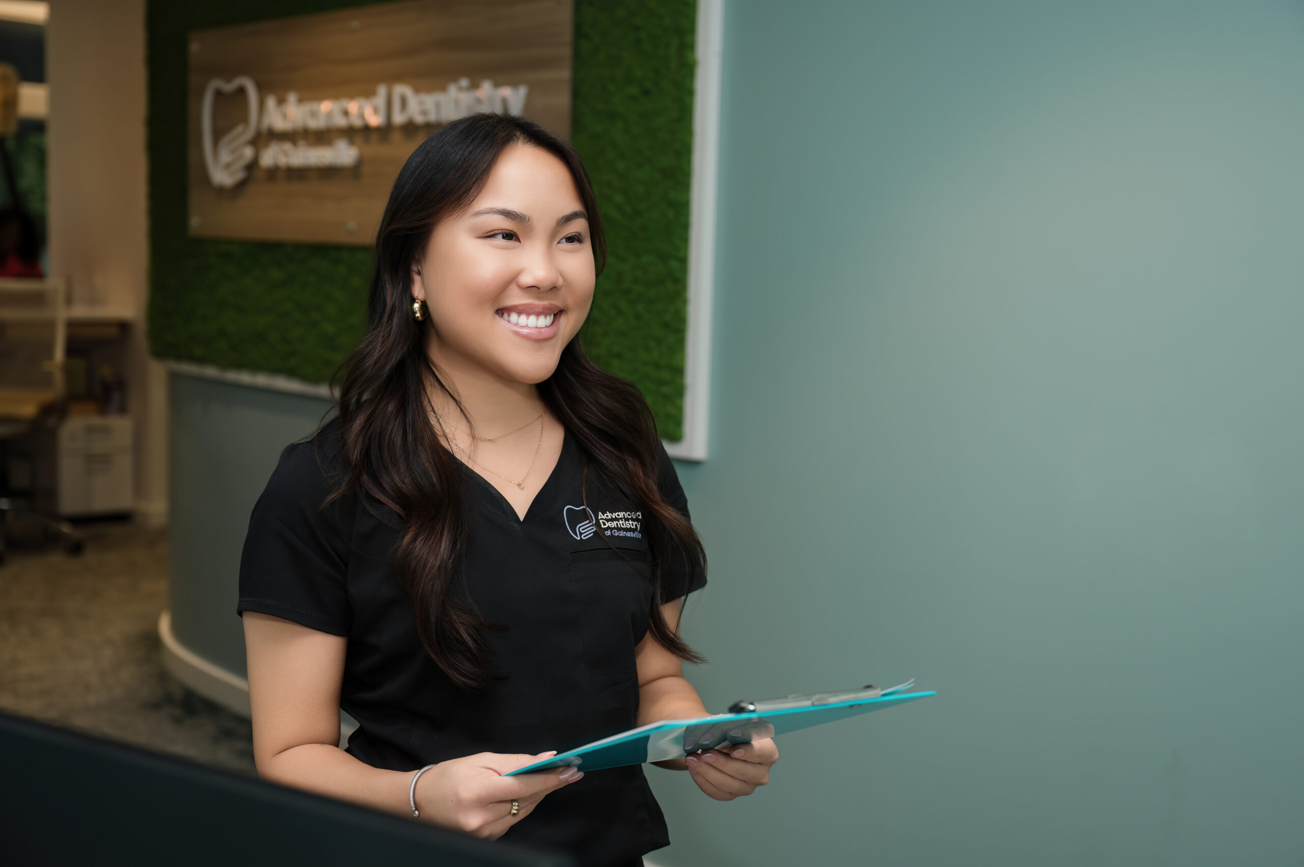 A worker standing near the front desk smiling and holding a clipboard