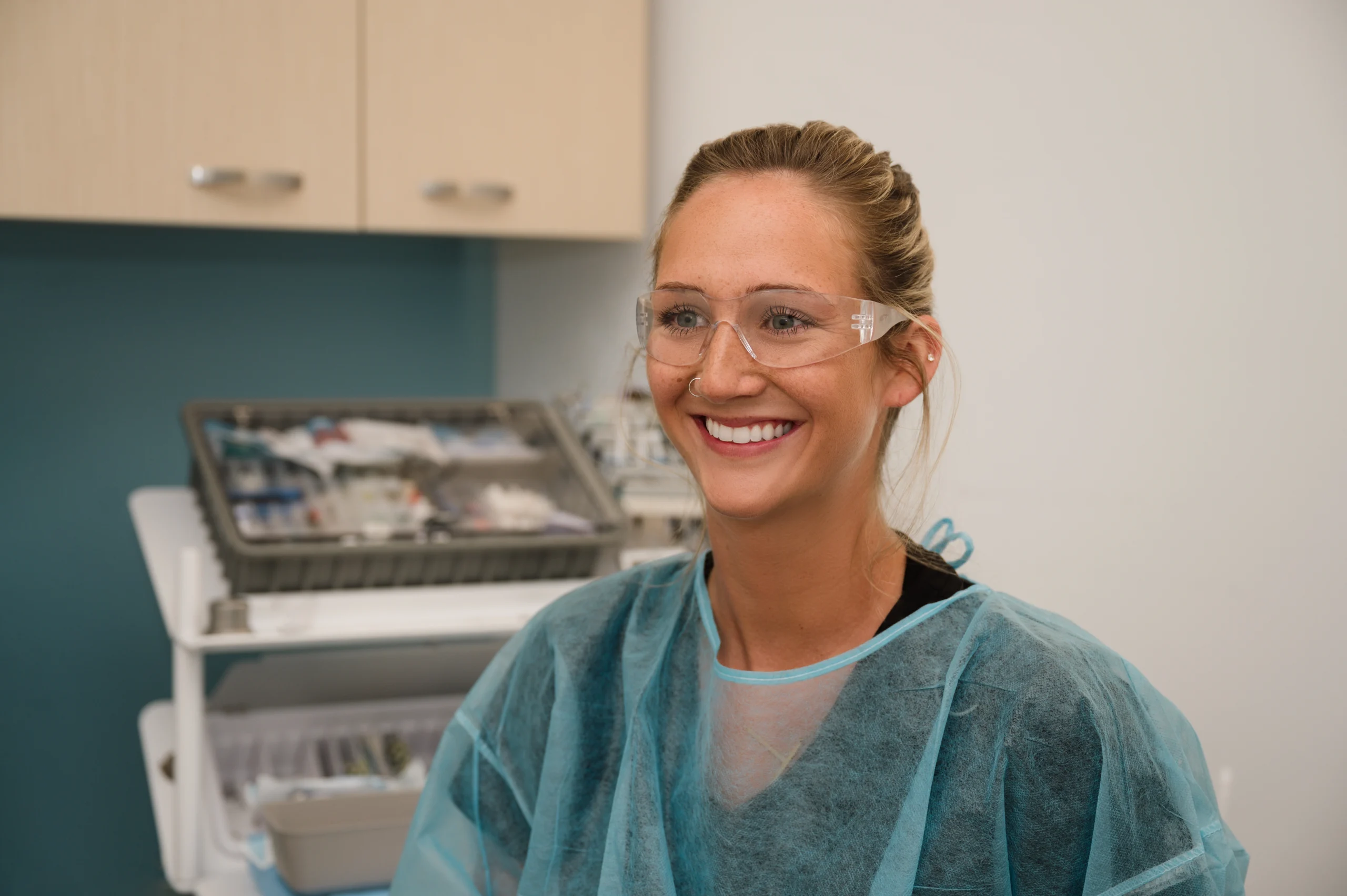 Trystan wearing safety glasses and a barrier jacket smiling in an exam room
